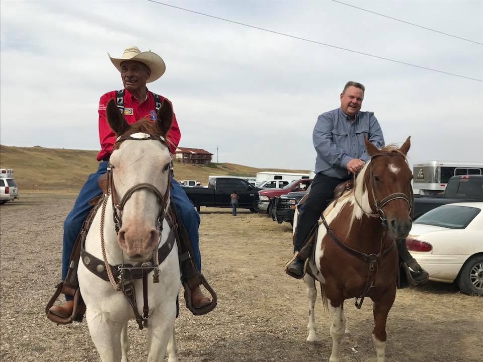 A.T. “Rusty” Stafne and then-U.S. Senator Jon Tester ride horses together at the Poplar Rodeo Grounds on the Fort Peck Reservation.