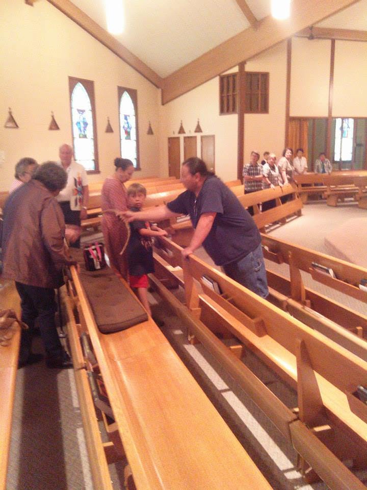 Kristofer Boyd shakes hands with people inside Our Lady of Lourdes Catholic Church after the Four Directions Song during a Saint Kateri honoring.