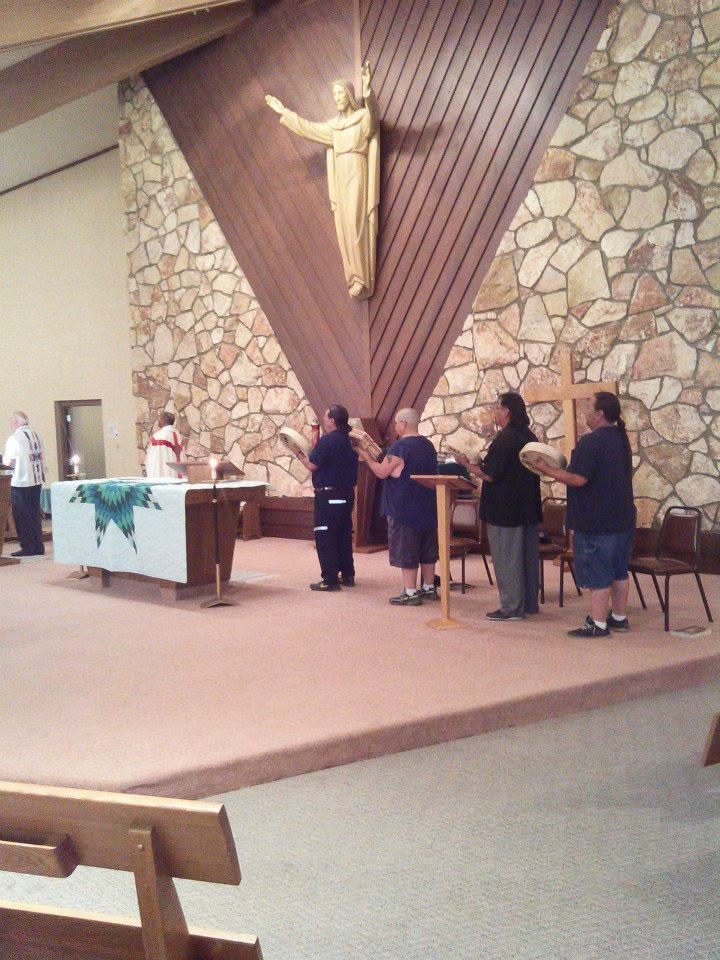 Four men sing the Four Directions Song with hand drums inside Our Lady of Lourdes Catholic Church during a Saint Kateri honoring in Poplar.