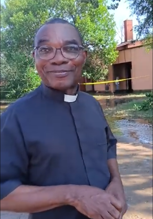 Father Anie Akama, priest of Our Lady of Lourdes Catholic Church in Poplar, stands near the church following the Aug. 25, 2026 fire.