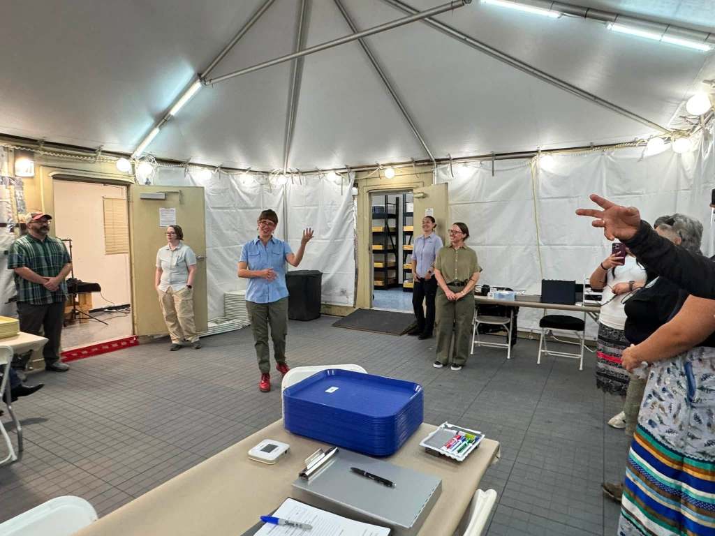Fort Peck delegation members meet with forensic analysis staff inside a tent at Carlisle Barracks during preparations for the repatriation of three Fort Peck children.
