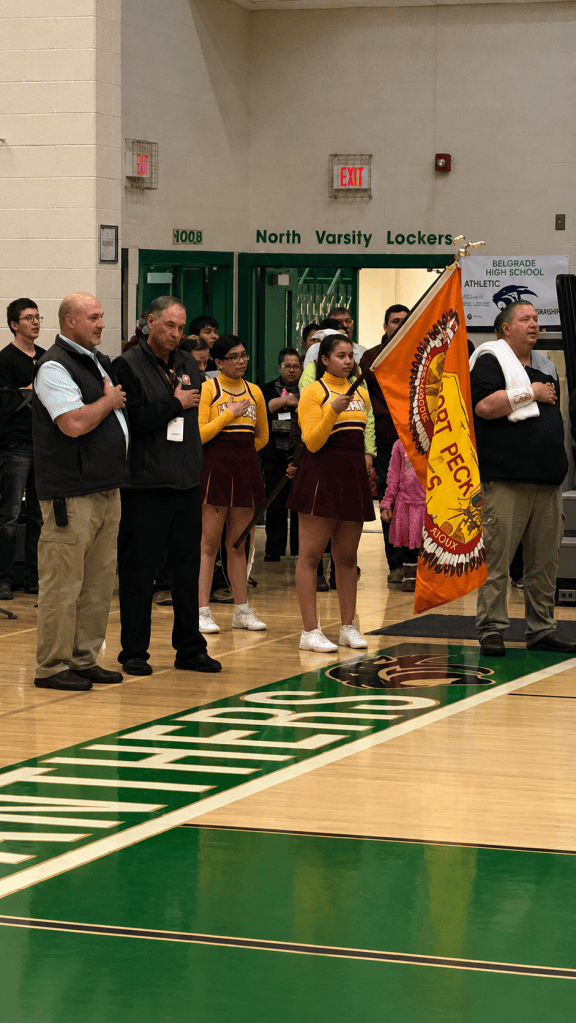 Student holds an orange Fort Peck Tribal Flag during a ceremony at Belgrade High School in Montana.