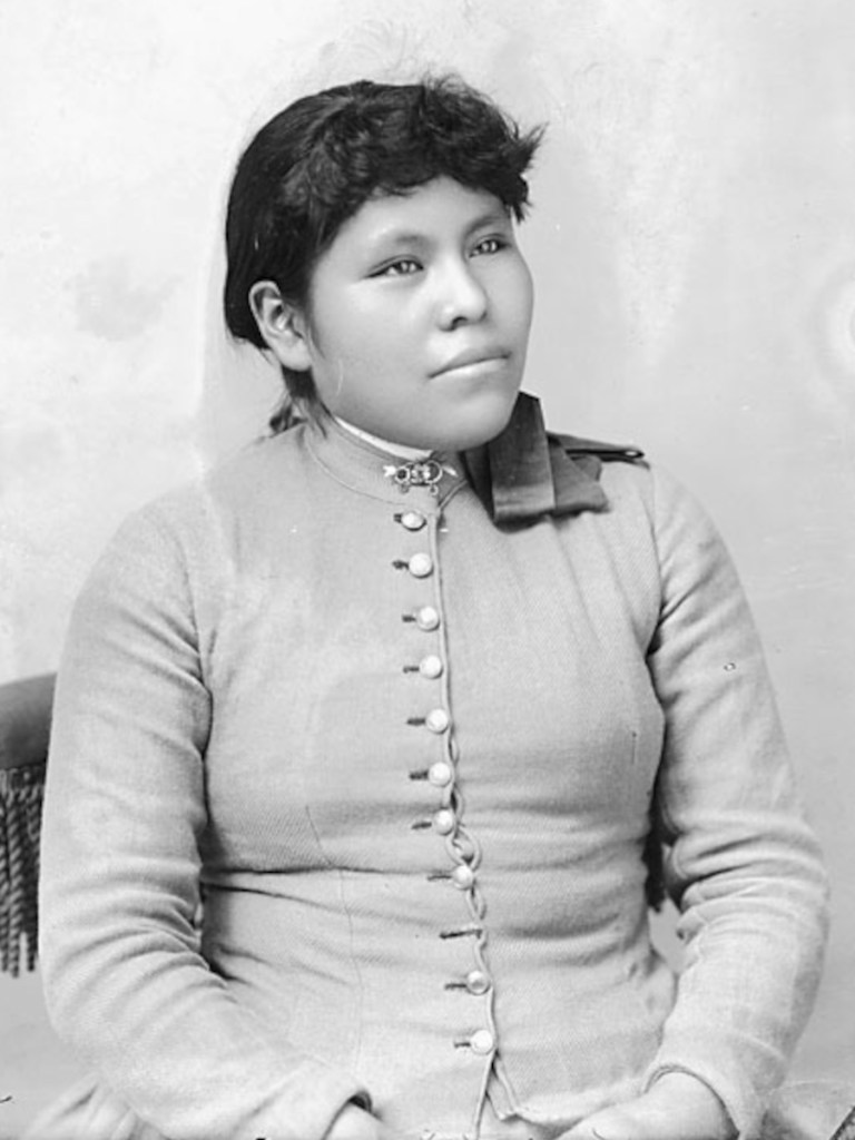 Historical black-and-white portrait of Christine Redstone seated in a buttoned school uniform at the Carlisle Indian Industrial School.
